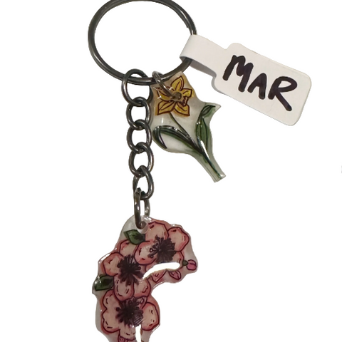 Keychain with floral design and 'MAR' tag on a light gray background