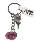 Keychain with floral charms and 'APR' tag on a light gray background