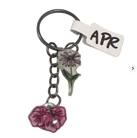 Keychain with floral charms and 'APR' tag on a light gray background