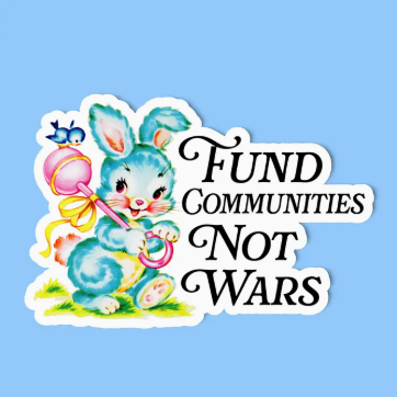 Sticker with a blue bunny holding a pink and yellow object, text 'Fund Communities Not Wars' on a light blue background.