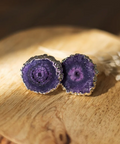 Purple geode-style earrings on a wooden surface