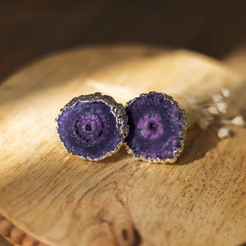 Purple geode-style earrings on a wooden surface