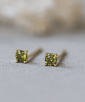 Pair of green gemstone stud earrings on a light gray background