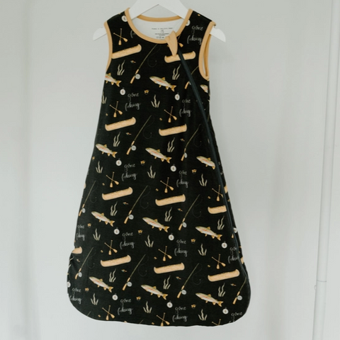 Black dress with beige patterns on a white hanger against a light gray background