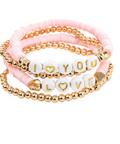 Three stacked beaded bracelets on a white background. The top bracelet is light pink cord with gold-toned beads.
