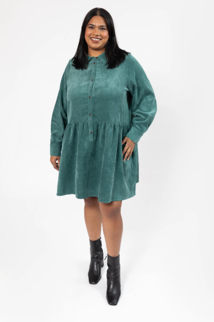 Woman wearing a green dress with black boots on a white background