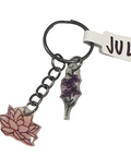 Keychain with floral charms and 'JUL' tag on a textured surface