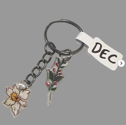Keychain with floral charms and a tag labeled 'DEC' on a light gray background