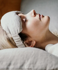 Person wearing a sleep mask lying on a pillow with a neutral background
