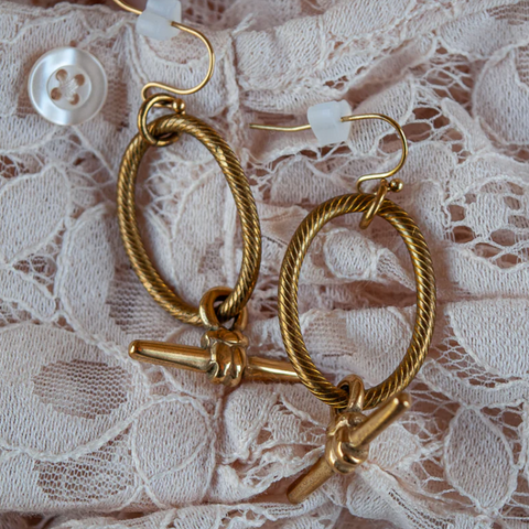 Gold hoop earrings with a clasp on a lace background
