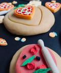 Decorative cookies shaped like hearts and flowers on a dark surface with cookie cutters.