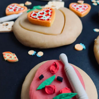 Decorative cookies shaped like hearts and flowers on a dark surface with cookie cutters.