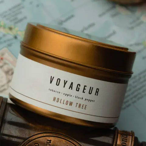 Voyageur Hollow Tree candle jar with gold lid on a textured surface