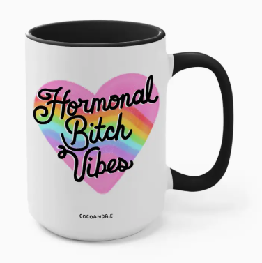 Mug with 'Hormonal Bitch Vibes' text inside a heart on a white background
