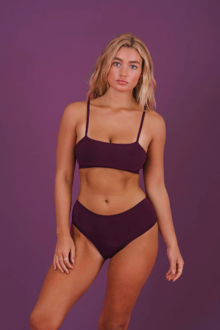 Woman wearing a purple bikini against a purple background