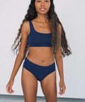 Woman wearing a navy blue bikini set against a plain background
