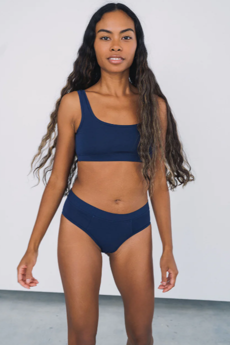 Woman wearing a navy blue bikini set against a plain background