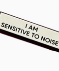 Badge with 'I AM SENSITIVE TO NOISE' text on a white background