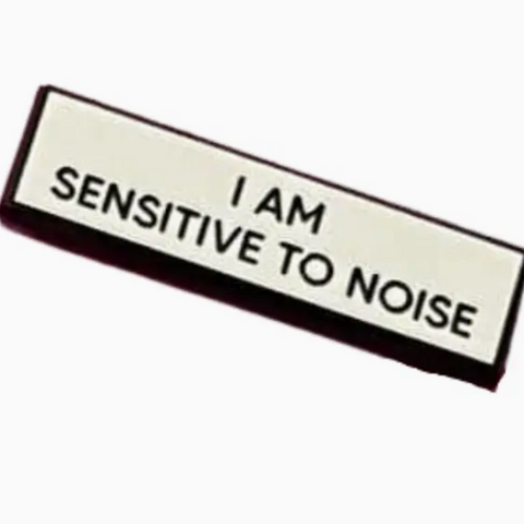 Badge with 'I AM SENSITIVE TO NOISE' text on a white background