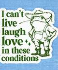 Cartoon frog wearing a cowboy hat with text 'I can't live laugh love in these conditions' on a blue background