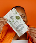 Person holding a 'Bless Berry' product against an orange background