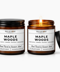 Two amber glass soy candles with black lids from Isle of Rose Candle Co. One candle is unlit with its lid off, and the other is lit with a visible flame, both against a clean white background.