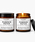 Two amber glass soy candles in black metal jars on a white background, one unlit and one lit with a visible flame. The labels read 'Isle of Rose Candle Co.
