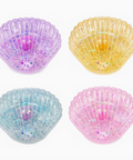 sea shell shaped sparkly squishies in 4 different colors. purple yellow blue pink