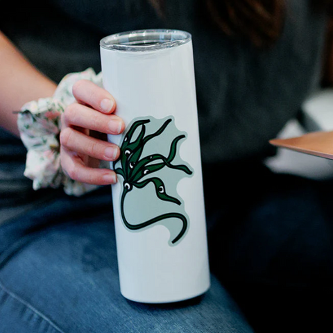 Person holding a white tumbler with a green dragon design.