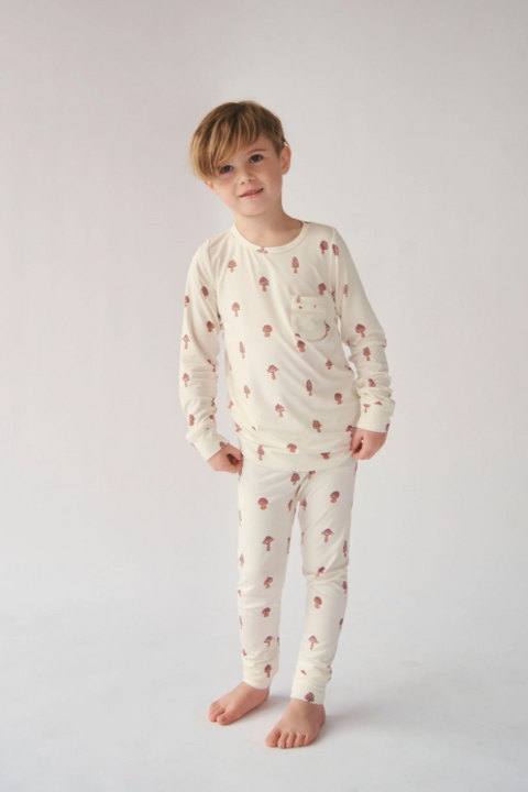 Child wearing a cream-colored pajama set with small patterns on a white background