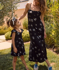 Mother and daughter wearing matching black floral dresses standing outdoors.