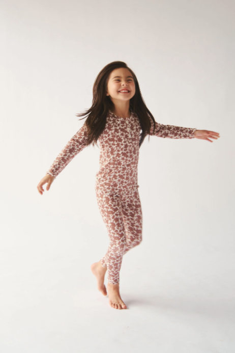 Young girl wearing a floral long-sleeve outfit on a white background