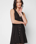 Woman wearing a black sleeveless dress with buttons on a white background