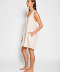 Woman wearing a beige sleeveless dress against a white background
