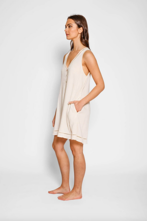 Woman wearing a beige sleeveless dress against a white background