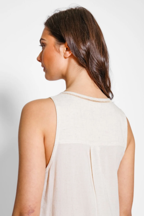 Woman wearing a light-colored sleeveless top against a plain background