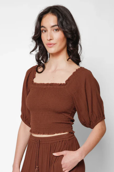 Woman wearing a brown top and skirt set against a white background