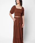 Woman wearing a brown top and long skirt set on a white background