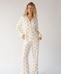 Woman wearing a white pajama set with small patterns on a plain background