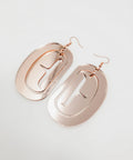 Large ovoid earrings in rose gold mirror acrylic with trigon cutout.
