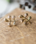 Gold leaf-shaped earrings on a wooden surface