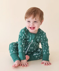Child wearing green pajamas with a pattern on a beige background