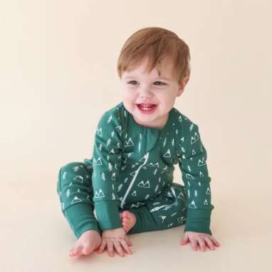 Child wearing green pajamas with a pattern on a beige background