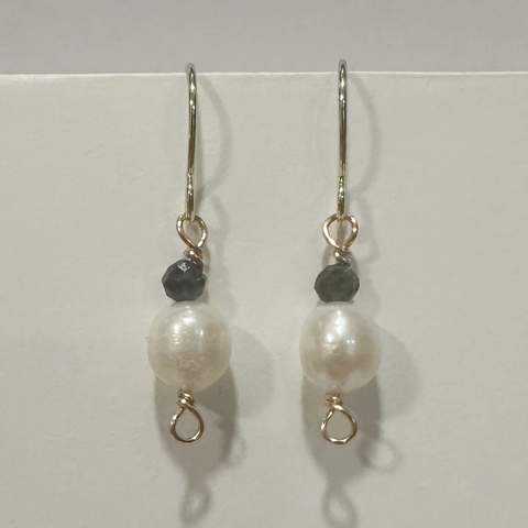Pair of pearl earrings with black beads on a white background