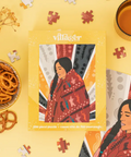 Village puzzle packaging with a woman in a red patterned shawl on a yellow background.