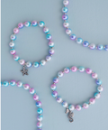 Set of pastel beaded necklaces with star and seahorse charms on a light blue background