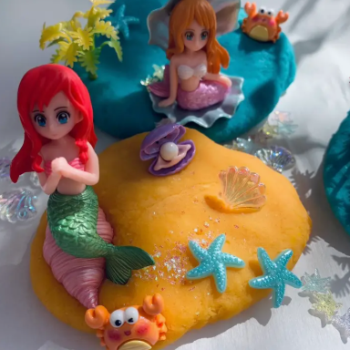 Mermaid figurines on a yellow base with starfish and other sea-themed decorations.