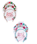 Two festive Christmas-themed headbands displayed on their original branded packaging cards against a solid white background. The top headband features a pink and white striped band with 'MERRY CHRISTMAS' spelled out in colorful glitter letters (red, green, gold, silver) decorated with small red holly leaves.