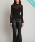 A woman modeling a black sheer long-sleeve mock neck top paired with black faux-leather flare pants, standing against a light gray studio background with a teal 'BEST SELLERS' banner in the top right corner.