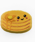 A cute, kawaii-style pancake or cookie decoration with a smiling face, black eyes, pink cheeks, and a small yellow coin detail, shown on a plain white background.